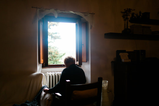 woman Indoors sitting facing window Tuscany Italy.
