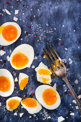Fototapeta na wymiar Hard boiled eggs, sliced in halves on wooden table