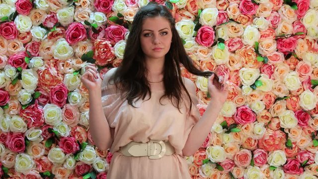 Portrait of young woman in pink dress, background of bright floral wall