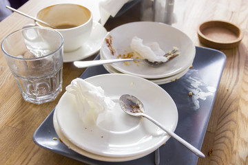 Carelessly laid dirty dishes after eating on woodwn table in dining room