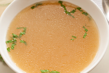 Bone broth made from chicken, served in a bowl with parsley
