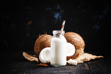 Coconut milk in a glass bottle, dark background, selective focus