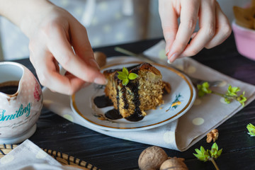 The housewife decorates a piece of cake with green leaves.