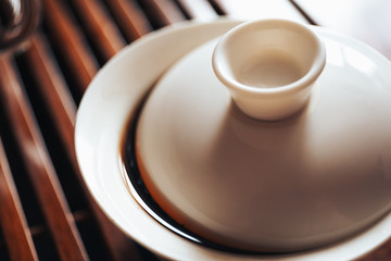 Chinese teacup or Gaiwan with black puerh tea on wooden tea board