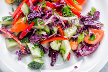Organic food. Fresh salad on white plate with onion, tomatoes, cucumber and cabbage. Close up and top view