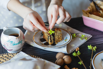 The housewife decorates a piece of cake with walnuts