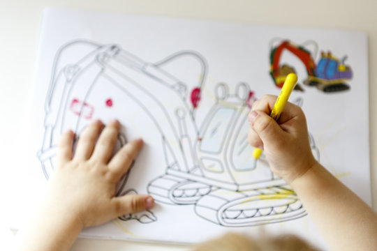 young child draw into coloring book