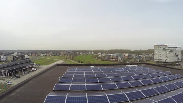 Aerial view low altitude flight over buildings roof filled with solar panels generating energy from sunshine sunstainable renewable energy also known as green energy modern building and technology 4k