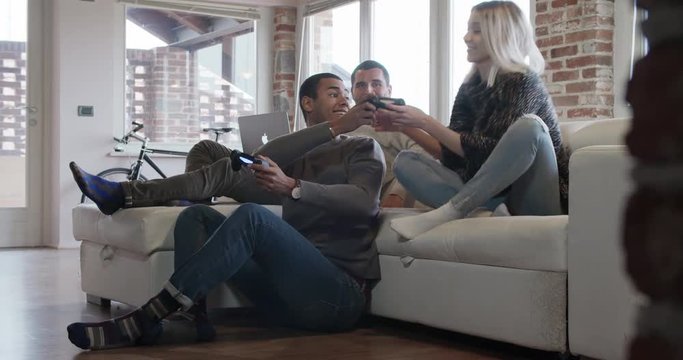 multiethnic group of friends people enjoy relaxing on couch playing videogames and having fun indoor in modern industrial house. 4k handheld video shot