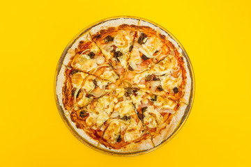 Homemade pizza on a yellow background.