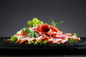 Food tray with delicious salami, pieces of sliced ham, sausage, tomatoes, salad and vegetable - Meat platter with selection