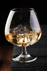glass of whiskey with ice on a wooden