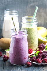 Multicolored berry and fruit smoothies, assorted in glass bottles, selective focus