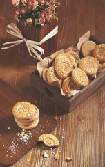 Top view of cookies in wooden box and dry roses