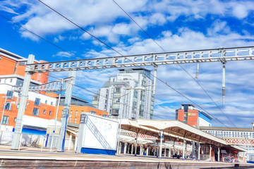 Urban mainline station with overhead live electric wires on a bright sunny day