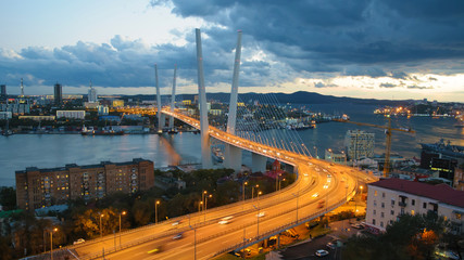 Fototapeta na wymiar Traffic of the port city by night. Golden bridge — cable-stayed bridge across the Zolotoy Rog Bay in Vladivostok. Was built in the framework of preparation to the APEC summit. Modern bridges Russia. 