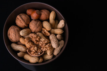 Different kinds of nuts in a plate on a black background