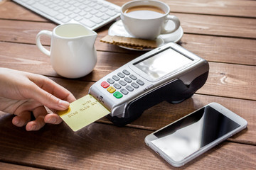 Payment for breakfast with card and terminal on wooden table background