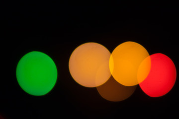 Colorful abstract blurry defocused bokeh lights on black background. Green, orange and red spots