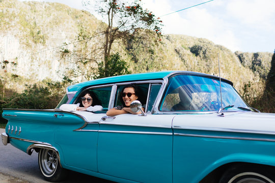 Twenty something laughs in 50's car ride in Vinales, Cuba