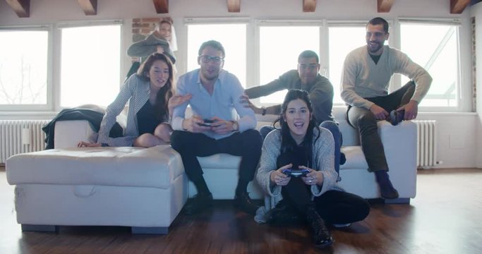 multiethnic group of friends people enjoy relaxing on couch playing videogames and having fun indoor in modern industrial house. 4k handheld slow motion video shot
