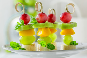 Delicious skewers with various fruits and mint for party
