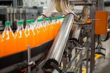 Orange drink bottles on production line in factory