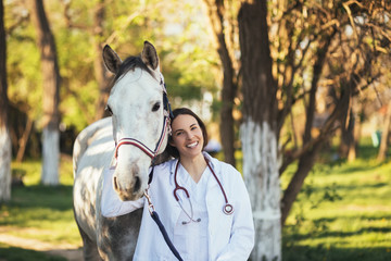 Vet petting a horse outdoors at ranch. Selective focus on woman.