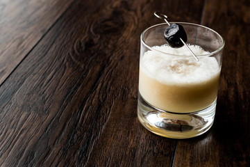 Whiskey sour cocktail served with olive.