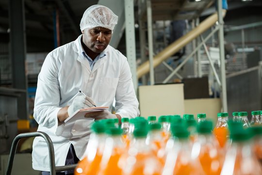 Male worker noting in juice factory