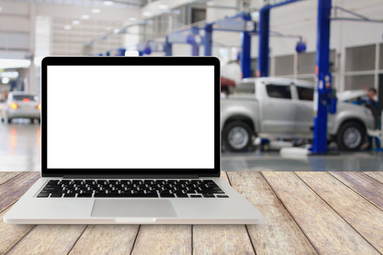 laptop on wooden table with blurred car service centre background