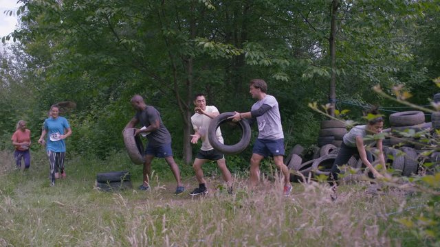  Competitors in endurance sports event running & stacking tyres. 