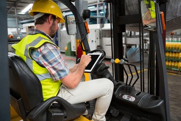 worker using tablet while sitting on forklift
