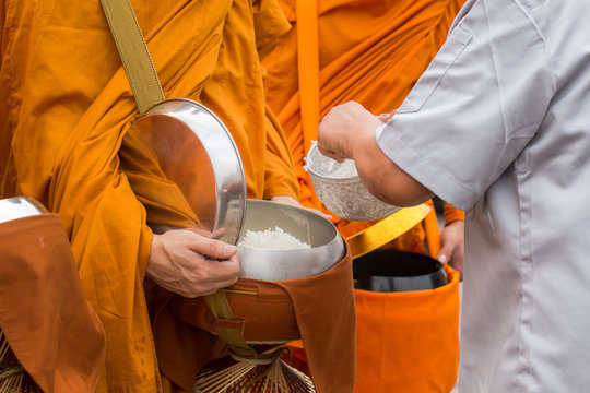 Buddhist monk of Thailand while stand in a row waiting people put rice and food offerings in their alms bowl for make merit
