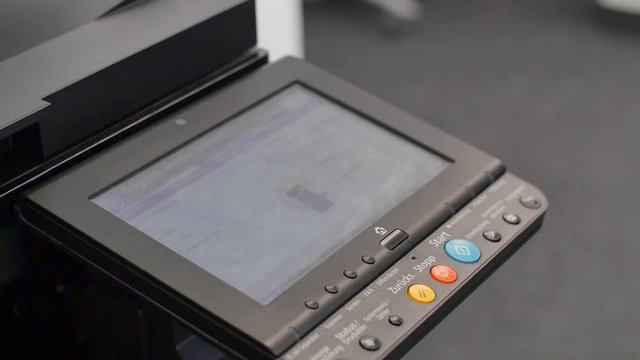 Hand pressing Start button on copy machine