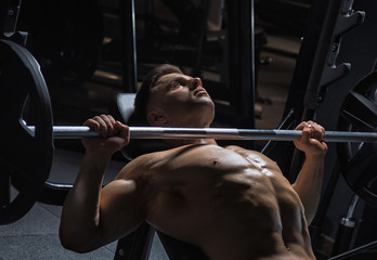 Fototapeta na wymiar Young handsome guy doing exercises in the gym