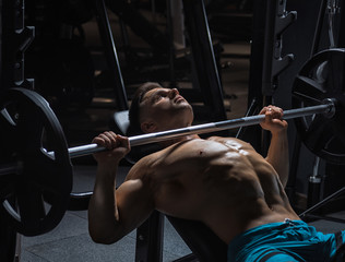 Fototapeta na wymiar Young handsome guy doing exercises in the gym