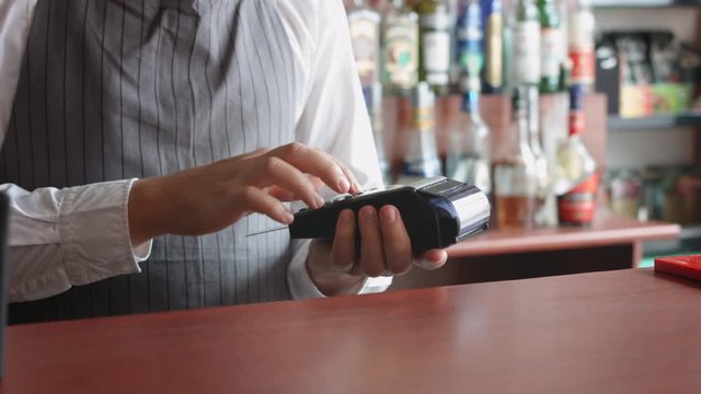 Man working in the bar accepting customer's cashless payment with credit card