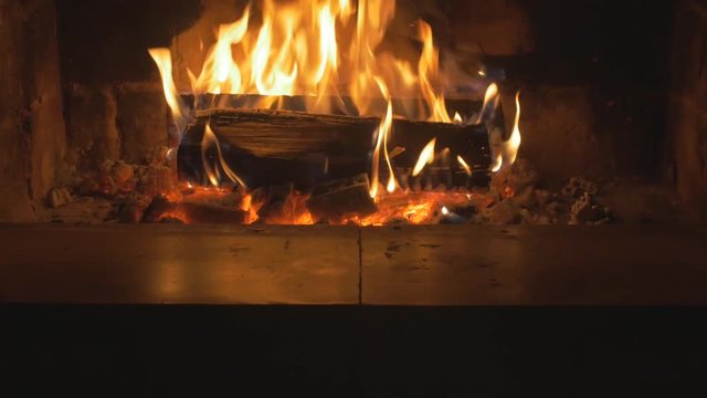 Warm cozy fire in a Home Fireplace. Real wood Burning in a Brick Fireplace tilt up. Home cosiness. Fireplace Medium Shot