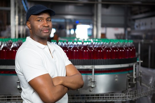 Confident male employee with arms crossed standing in factory