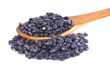 Black beans in a wooden spoon on a white background