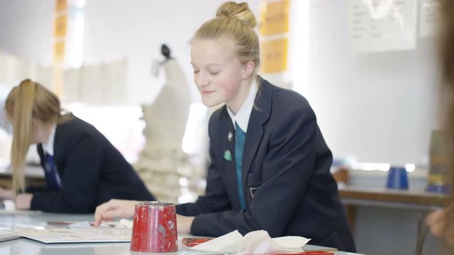 Group of teen girls in school art class, focus on 1 girl talking to her frien