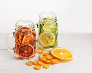 Two lemonades on the jars with red orange, lime and lemon inside