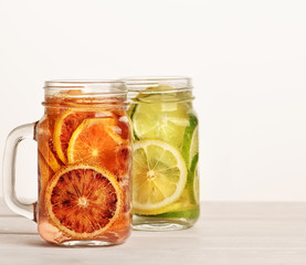 Two lemonades on the jars with red orange, lime and lemon inside