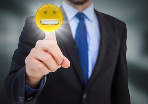 Business man pointing at emoji with flare in blurry grey room