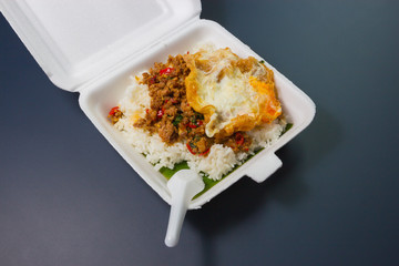 Rice topped with stir-fried pork and basil on foam box