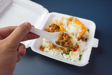 Rice topped with stir-fried pork and basil on foam box