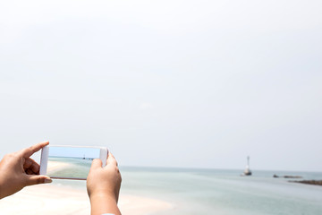 hand hold and touch screen smart phone,cellphone over blurred beautiful beach background