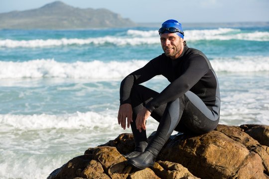 Portrait of confident athlete sitting on rock 