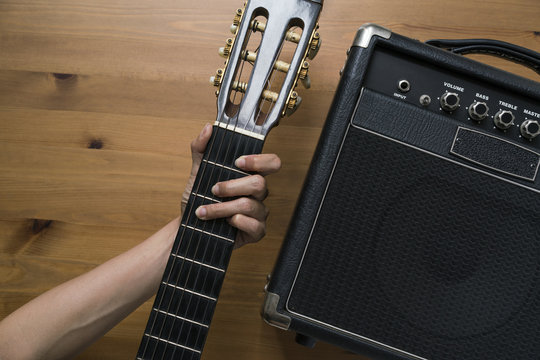 Guitar amplifier and woman hand holding a guitar on wood table